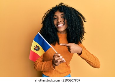 African American Woman With Afro Hair Holding Moldova Flag Smiling Happy Pointing With Hand And Finger 