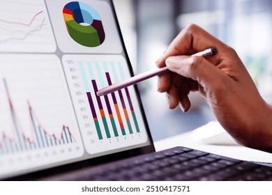 African American woman analyzing financial data on laptop screen in hybrid office setting for digital entrepreneurship KPI dashboard.