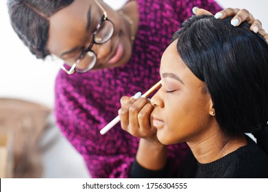 African American Woman Applying Make-up By Make-up Artist At Beauty Saloon.