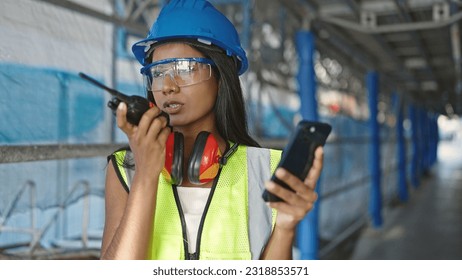 African american woman architect talking on walkie-talkie looking smartphone screen at street - Powered by Shutterstock