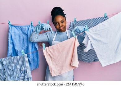 African American Woman With Braided Hair Washing Clothes At Clothesline Pointing Down Looking Sad And Upset, Indicating Direction With Fingers, Unhappy And Depressed. 