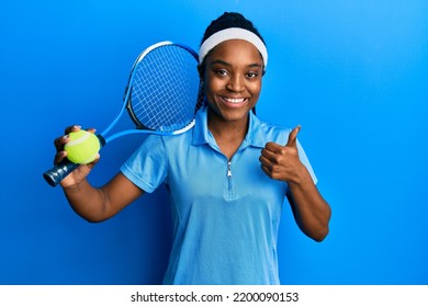 African american woman with braided hair playing tennis holding racket and ball smiling happy and positive, thumb up doing excellent and approval sign  - Powered by Shutterstock