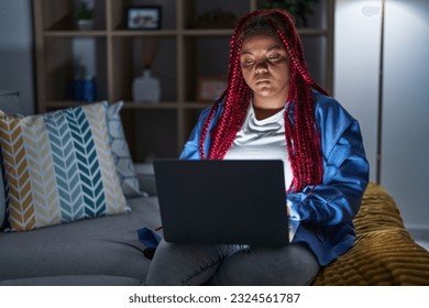 African american woman with braided hair using computer laptop at night skeptic and nervous, frowning upset because of problem. negative person.  - Shutterstock ID 2324561787