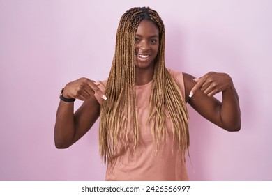 African american woman with braided hair standing over pink background looking confident with smile on face, pointing oneself with fingers proud and happy.  - Powered by Shutterstock