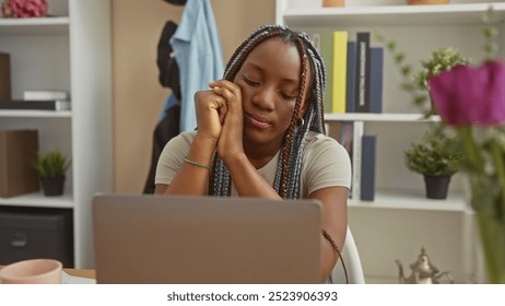 African american woman with braids contemplating indoors at her apartment beside a laptop. - Powered by Shutterstock