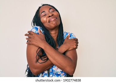 African american woman with braids wearing casual summer clothes hugging oneself happy and positive, smiling confident. self love and self care 