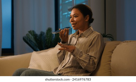 African American woman businesswoman record voice message on speaker phone send audio voicemail dictate information in microphone AI mobile assistance speak cellphone talk loudspeaker at evening home - Powered by Shutterstock