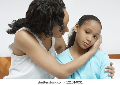 African American Woman Comforting Sick Daughter At Home