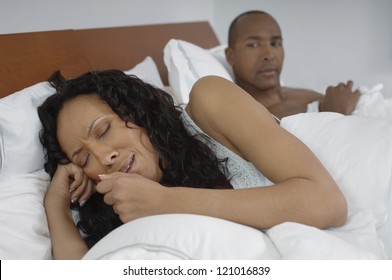 African American Woman Coughing In Bed With Man In Background