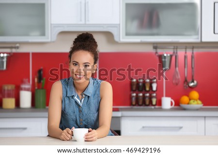 African American woman with a cup of coffee in kitchen