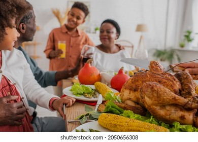 African American Woman Cutting Traditional Turkey Near Blurred Family