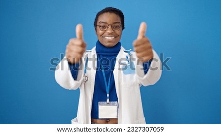 African american woman doctor doing thumbs up over isolated blue background