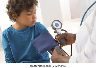 African American Woman Doctor Taking A Child Blood Pressure.