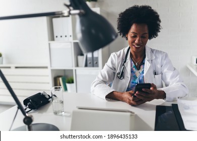 African American Woman Doctor Working At Her Office Online Using Portable Inormation Device. Telemedicine Services. Primary Care Consultations, Psychotherapy, Emergency Services. 