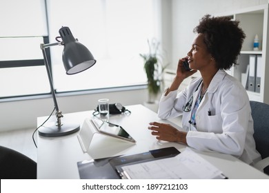 African American Woman Doctor Working At Her Office Online Using Portable Inormation Device. Telemedicine Services. Primary Care Consultations, Psychotherapy, Emergency Services. 