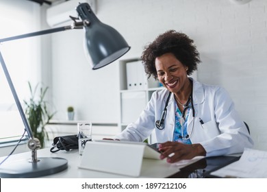 African American Woman Doctor Working At Her Office Online Using Portable Inormation Device. Telemedicine Services. Primary Care Consultations, Psychotherapy, Emergency Services. 