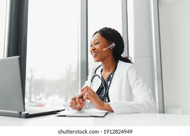 African American Woman Doctor Working At Her Office Online Using Portable Inormation Device. Telemedicine Services. Primary Care Consultations, Psychotherapy, Emergency Services.