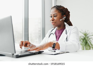 African American Woman Doctor Working At Her Office Online Using Portable Inormation Device. Telemedicine Services. Primary Care Consultations, Psychotherapy, Emergency Services.