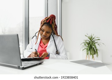 African American Woman Doctor Working At Her Office Online Using Portable Inormation Device. Telemedicine Services. Primary Care Consultations, Psychotherapy, Emergency Services.