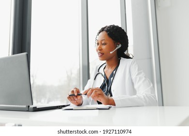 African American Woman Doctor Working At Her Office Online Using Portable Inormation Device. Telemedicine Services. Primary Care Consultations, Psychotherapy, Emergency Services.