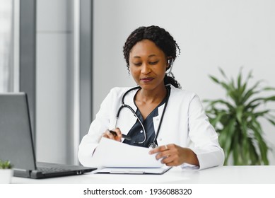 African American Woman Doctor Working At Her Office Online Using Portable Inormation Device. Telemedicine Services. Primary Care Consultations, Psychotherapy, Emergency Services.