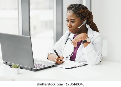 African American Woman Doctor Working At Her Office Online Using Portable Inormation Device. Telemedicine Services. Primary Care Consultations, Psychotherapy, Emergency Services.