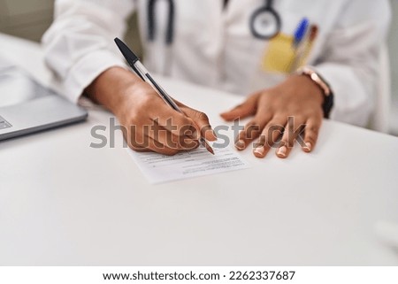 African american woman doctor writing on covid-19 vaccination record card at clinic