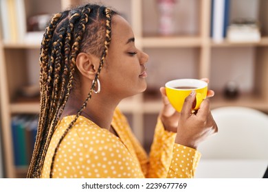 African american woman drinking coffee sitting on table at home - Powered by Shutterstock