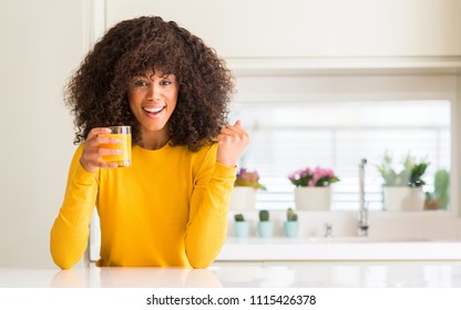 African american woman drinking orange juice in a glass screaming proud and celebrating victory and success very excited, cheering emotion - Powered by Shutterstock