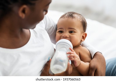 African American woman feeding her child from baby bottle