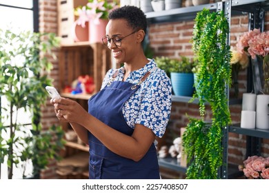 African american woman florist smiling confident using smartphone at florist - Powered by Shutterstock