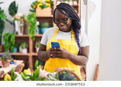 African american woman florist smiling confident using smartphone at florist - Powered by Shutterstock