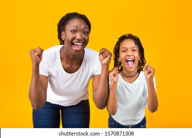 African American Woman And Girl Celebrating Success, Clench Fists And Exclaim With Triumph Over Yellow Background