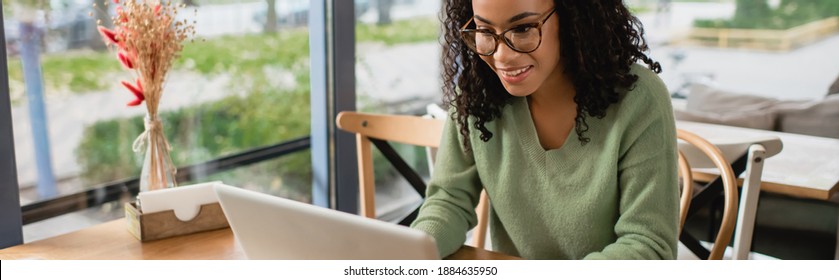 African American Woman In Glasses Using Laptop In Cafe, Banner