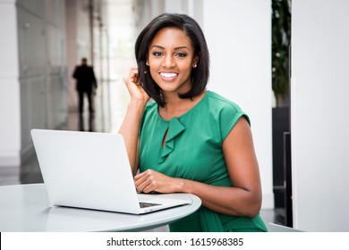 African American Woman In Green Dress In Modern Corporate Building Lobby 