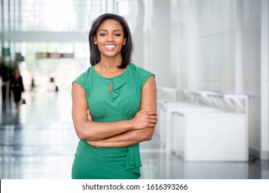 African American woman in green dress in modern corporate building lobby  - Shutterstock ID 1616393266