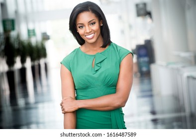 African American woman in green dress in modern corporate building lobby 