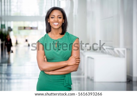 African American woman in green dress in modern corporate building lobby 