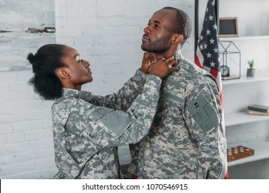 African American Woman Helping Man To Get Dressed In Camouflage Clothes