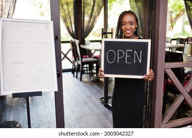 African American Woman Hold Open Welcome Sign Board In Modern Cafe Coffee Shop Ready To Service, Restaurant, Retail Store, Small Business Owner.