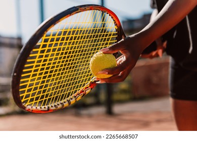 African american woman hold racket and yellow green ball, playing tennis match on clay court surface on weekend free time sunny day. Female player ready to serve. Professional sport concept
 - Powered by Shutterstock