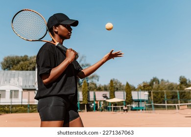 African american woman hold racket and yellow green ball, playing tennis match on clay court surface on weekend free time sunny day. Female player ready to serve. Professional sport concept
