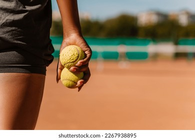 African american woman hold yellow green balls, playing tennis match on clay court surface on weekend free time sunny day. Female player ready to serve. Professional sport concept

 - Powered by Shutterstock