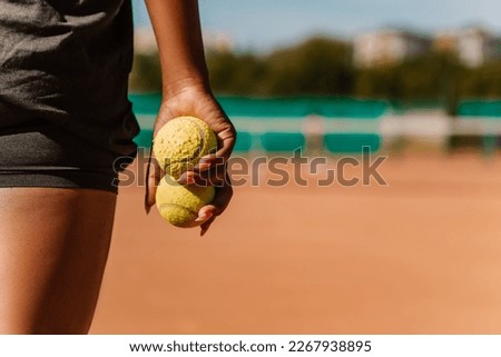 African american woman hold yellow green balls, playing tennis match on clay court surface on weekend free time sunny day. Female player ready to serve. Professional sport concept

