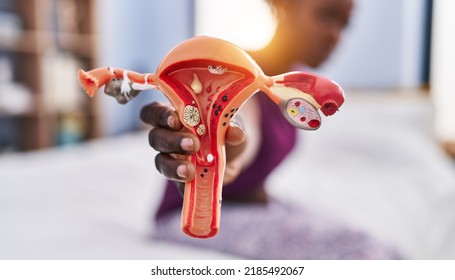 African American Woman Holding Anatomical Model Of Fallopian Tube At Bedroom