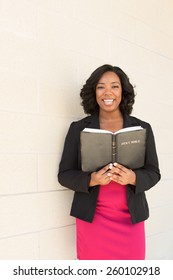 African American Woman Holding A Bible Looking At The Camera And Smiling.