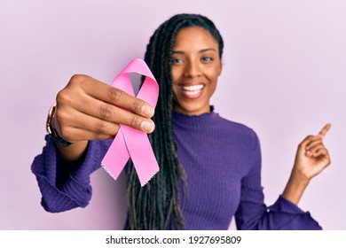 African American Woman Holding Pink Cancer Ribbon Smiling Happy Pointing With Hand And Finger To The Side 