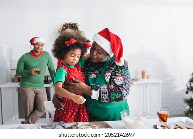 African American Woman Hugging Granddaughter While Cooking Together In Kitchen