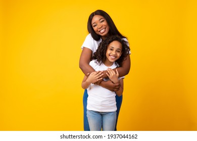 African American woman hugging her smiling daughter from the back