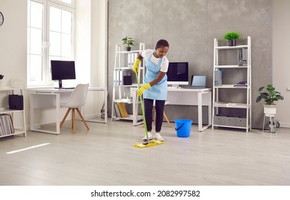 African American woman janitor with mop clean office floor with sanitizer liquid detergent. Black ethnic female housekeeper cleaner wash dirt dust in company workplace. Housekeeping concept. - Shutterstock ID 2082997582